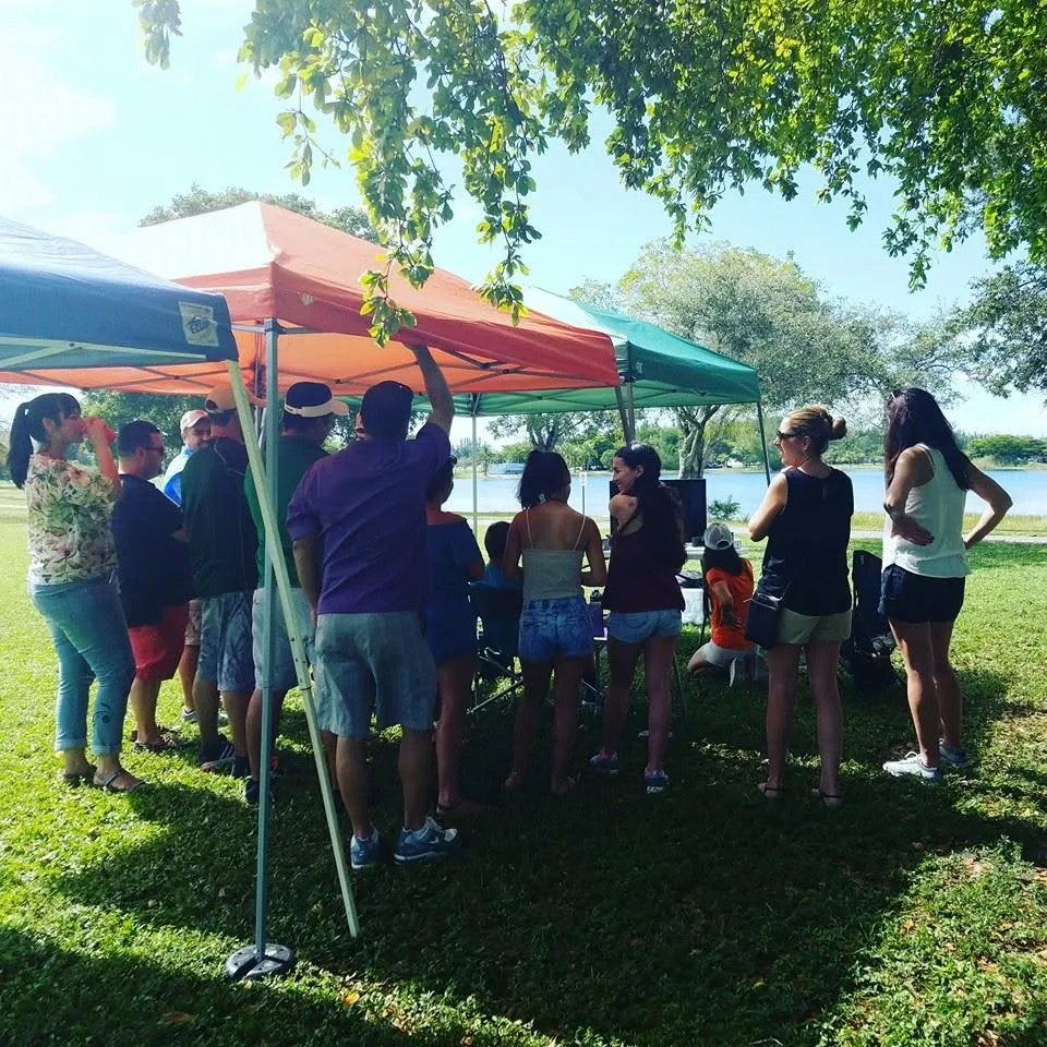 Families under pop-up tents at a class picnic