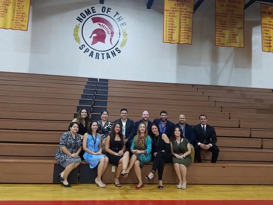 Classmates on the gym bleachers under the Home of the Spartans logo