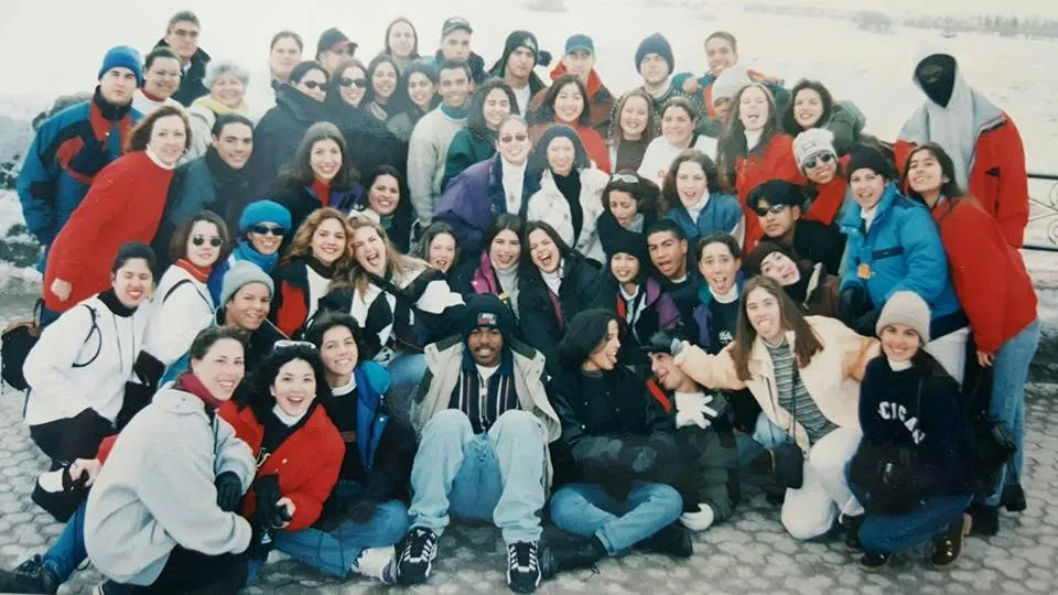 A big group of classmates in jackets, squeezed together for a trip photo